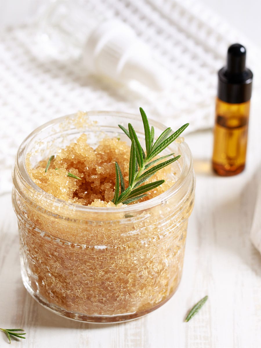 Brown sugar scrub with rosemary and tincture bottle.