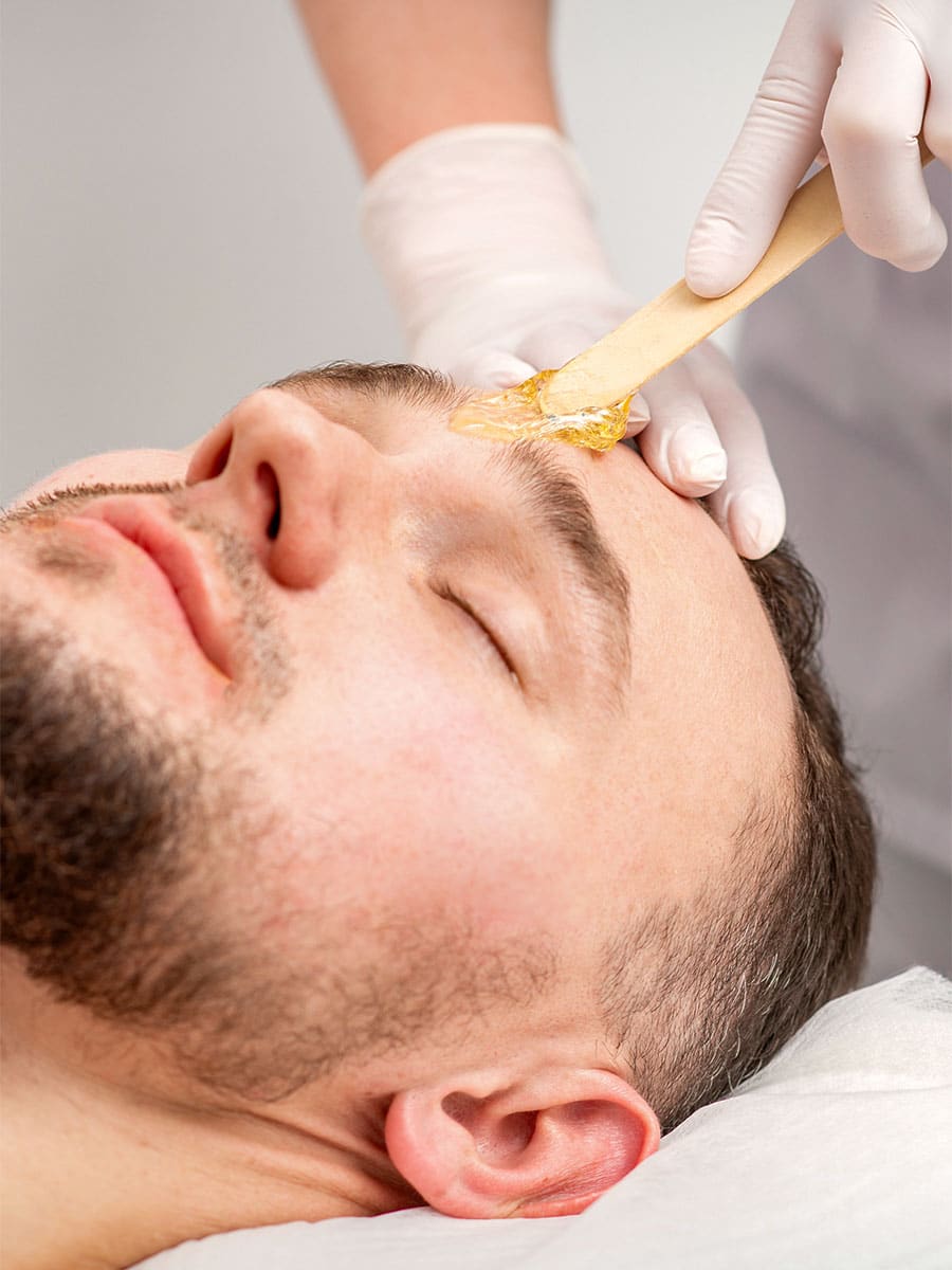 Man receiving eyebrow waxing treatment.